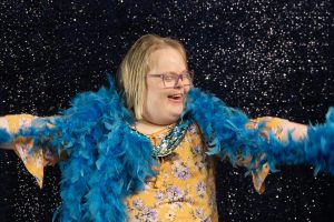 Nainen katsoo hymyillen yllään olevaa turkoosia sulkapuuhkaa.